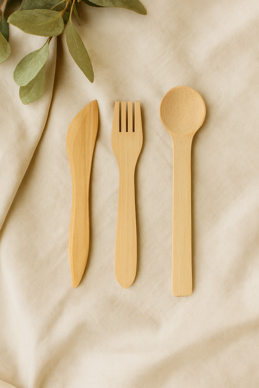 Zestaw drewnianych sztućców ekologicznych – nóż, widelec i łyżka z buku na beżowym płótnie z gałązką eukaliptusa, naturalne oświetlenie, styl rustykalny.
