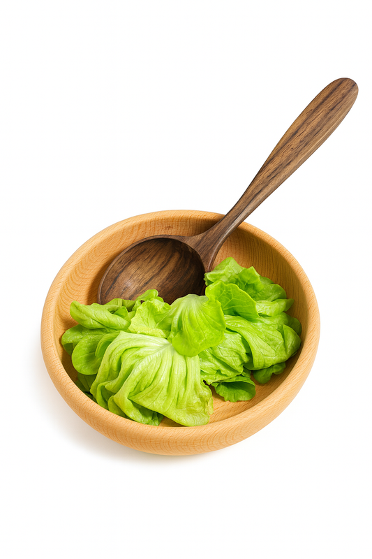 Drewniana miska z jasno-brązowego drewna wypełniona świeżą, zieloną sałatą i ciemniejszą drewnianą łyżką do serwowania. Produkt sfotografowany na białym tle – naturalny, rustykalny zestaw kuchenny Chłopcy z Rancza.