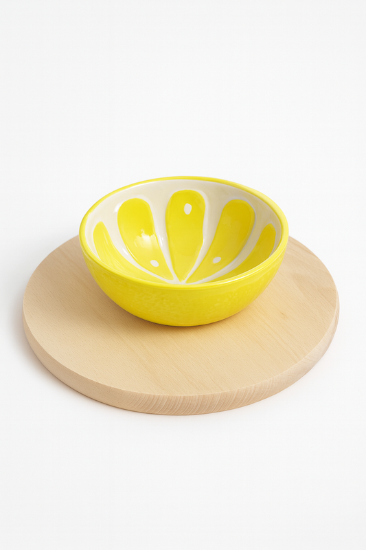 Żółta ceramiczna miseczka w kształcie plastra cytryny ustawiona na okrągłej drewnianej desce z litego drewna bukowego – produkt do kuchni, idealny do serwowania przekąsek lub dekoracji stołu.