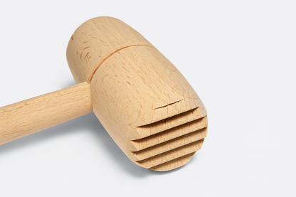 Drewniany tłuczek do mięsa z okrągłą głowicą i żłobioną powierzchnią roboczą – wykonany z naturalnego, jasnego drewna bukowego, idealny do codziennego użytku w kuchni.