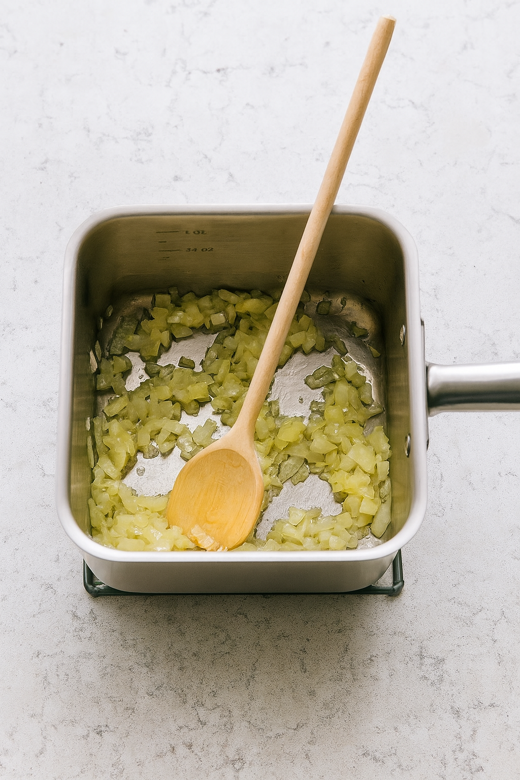 Drewniana łyżka kuchenna mieszająca smażącą się cebulę w kwadratowym garnku ze stali nierdzewnej – naturalna scena kuchni.