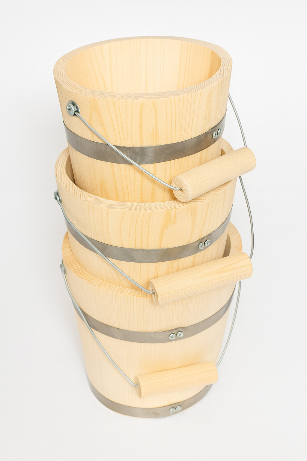 Zestaw trzech drewnianych wiader z jodły, ustawionych jedno w drugim. Każde wiadro ma metalowe obręcze i wygodny uchwyt z drewnianą rączką. Naturalne drewno o jasnym kolorze i widocznym usłojeniu – idealne do sauny, ogrodu lub jako element dekoracyjny w stylu rustykalnym.