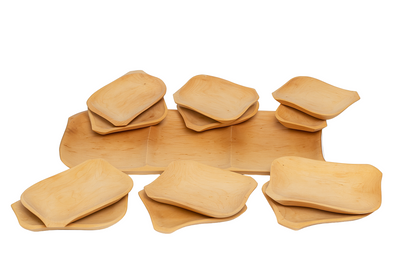 Zestaw prostokątnych talerzy z jasnego drewna ustawionych na białym tle. Widać dziewięć talerzy o różnych rozmiarach, ułożonych w kilku stosach. Gładkie powierzchnie i naturalny odcień drewna podkreślają ręczne wykonanie i organiczny charakter produktów.