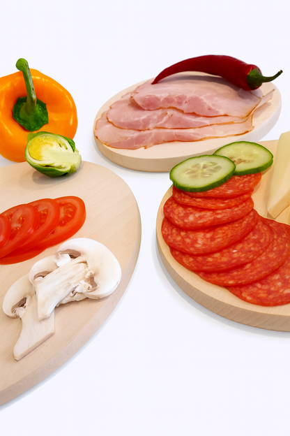 Kompozycja drewnianych desek z wędlinami, salami, warzywami i żółtym serem – naturalne deski bukowe do kuchni i jadalni.